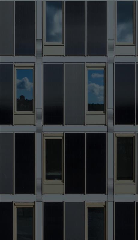 Close-up of a modern dark-clad building facade with grid panels, bronze-framed narrow windows, and a vertical light-green accent panel.